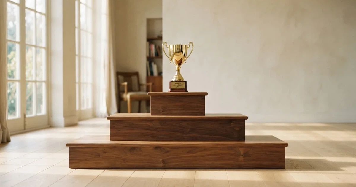 Podie af træ med tre trin i et lyst lokale og en enkelt guldfarvet pokal øverst, set forfra.